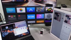 Sestava Apple TV, MacBooku a iPadu na stole během prezentace nového hardwaru