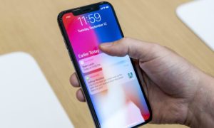 Ruka drží iPhone X se zamčenou obrazovkou a zobrazenými upozorněními