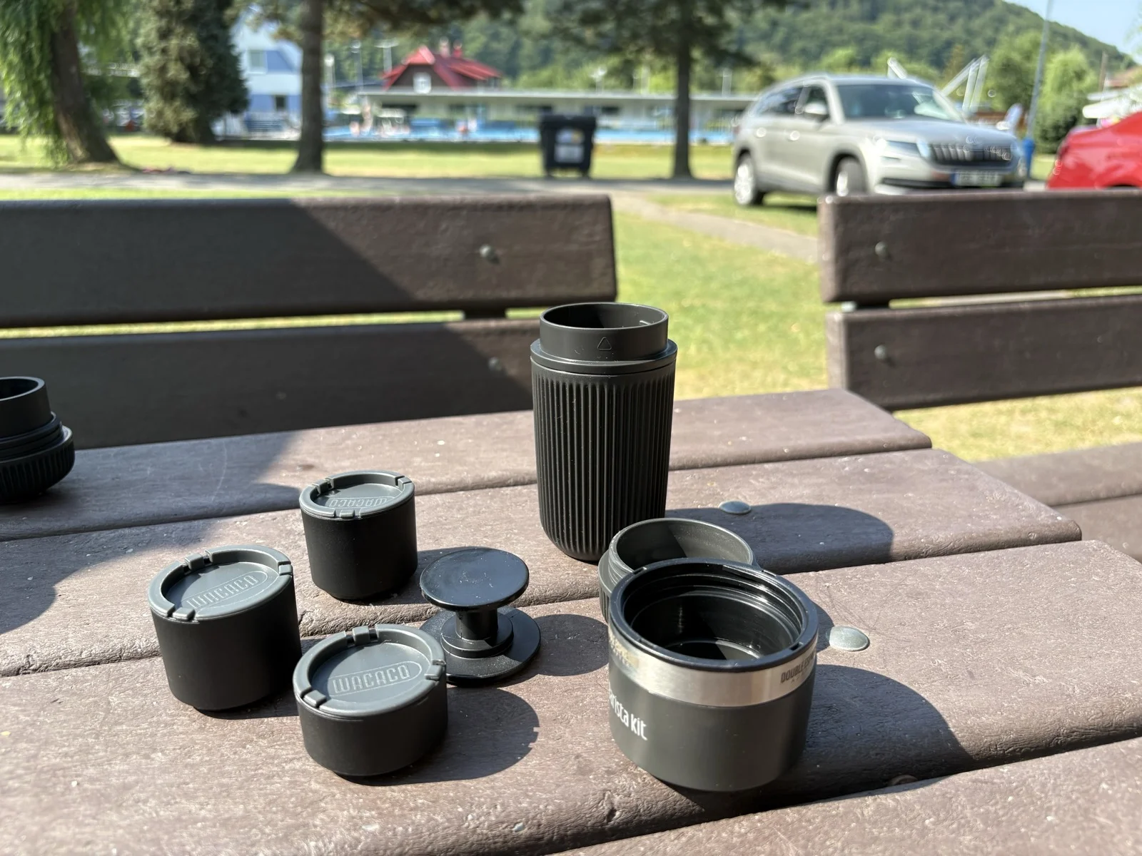 Rozložený Wacaco Barista Kit s košíky, tamperem, nádržkou a adaptérovým kroužkem na stole