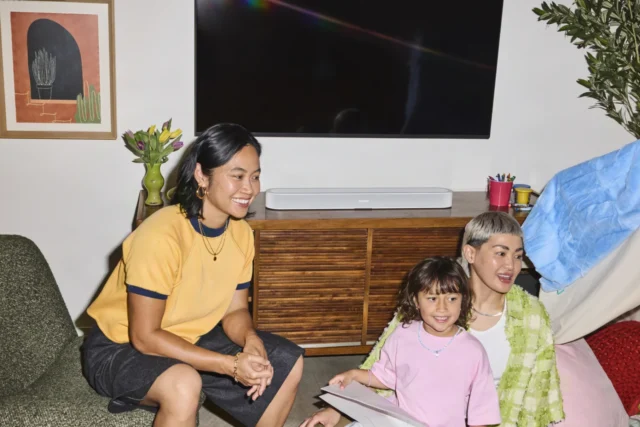 Bílý soundbar Sonos Beam Ultra na dřevěné komodě pod televizorem v obývacím pokoji Bílý soundbar Sonos Beam Ultra na dřevěné komodě pod televizorem v obývacím pokoji