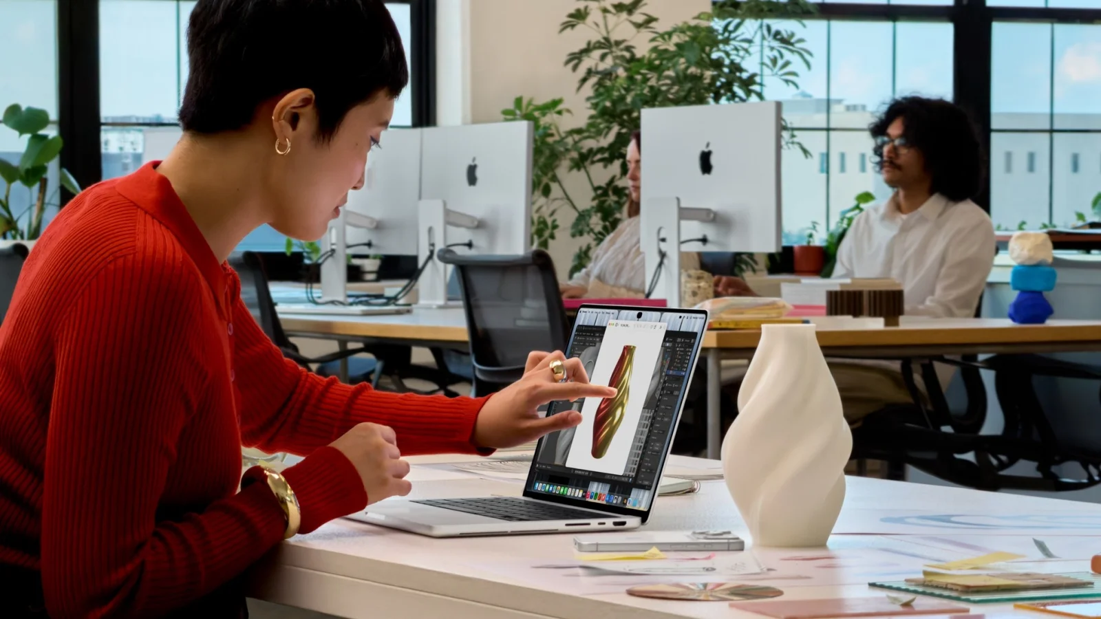 Žena ovládá prstem 3D model na displeji MacBooku Pro s PROLED XDR