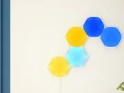 Světla Nanoleaf podporují HomeView: v Česku je dál ovládá Domácnost Pět rozsvícených šestiúhelníkových panelů Nanoleaf Shapes ve žluté a modré barvě na světlé stěně nad jídelním stolem