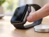 Jak restartovat, vypnout a resetovat Apple Watch (i když nereagují) Prst na postranním tlačítku Apple Watch ležících na stole vedle nabíječky