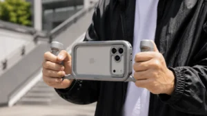 iPhone v rámu ShiftCam ProRig se dvěma šedými rukojeťmi v rukou natáčejícího člověka